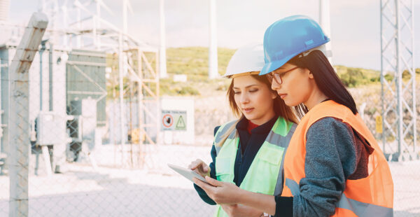 Two female utility workers conducting power checks near power utilities