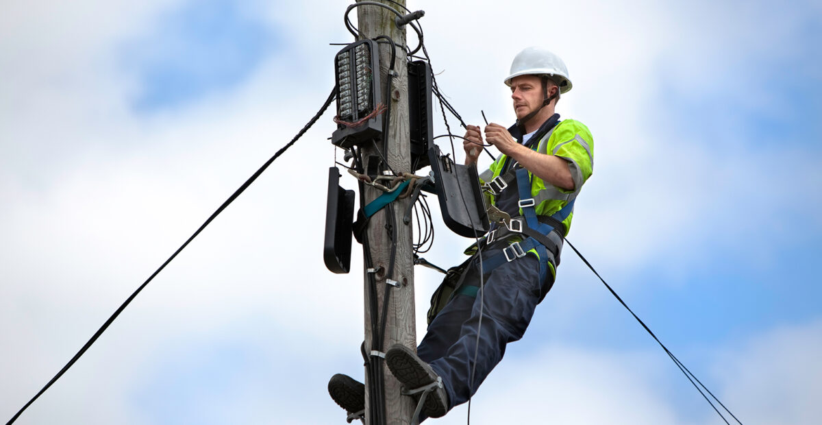 Utilities worker repairing. telephone pylon.